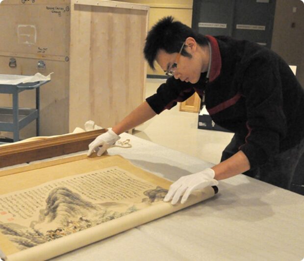 Photo of a conservator looking at a Chinese painting