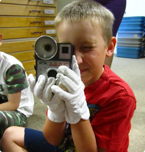 A boy wearing gloves holding a camera