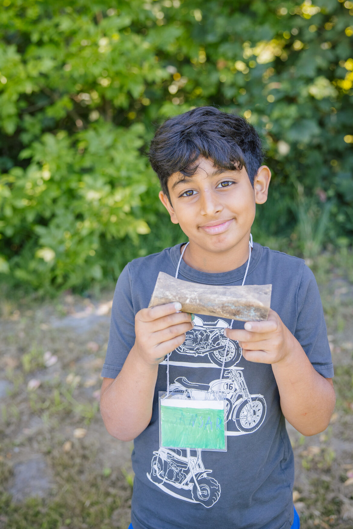 Young child with short black hair holds unidentified object with two hands.